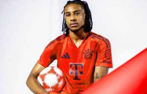 Michael Olise unveiling at Bayern Munich holding ball in his hand